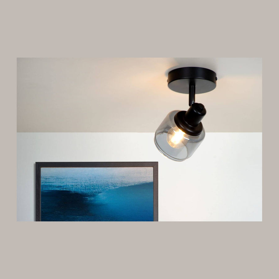 Plafonnier noir allumé, verre fumé orienté vers un tableau bleu abstrait