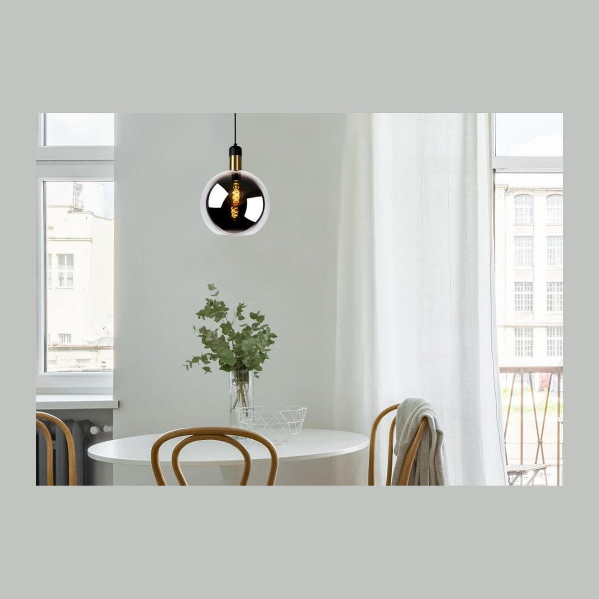 Suspension en verre fumé allumée au-dessus d'une table blanche dans un intérieur lumineux