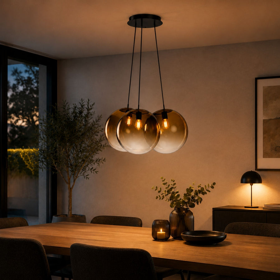 Suspension trois globes ambrés allumée au-dessus d'une table à manger en bois