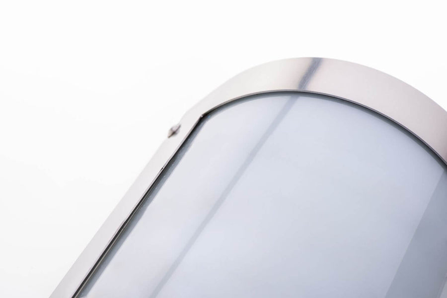 Gros plan sur le bord supérieur incurvé en inox, vis apparentes et diffuseur translucide.
