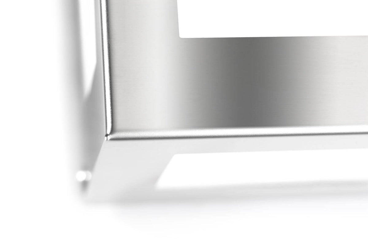 Gros plan sur l'angle en inox brossé et le cadre blanc du luminaire extérieur.