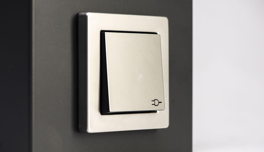 Gros plan sur l'interrupteur argenté avec icône de prise sur le luminaire.