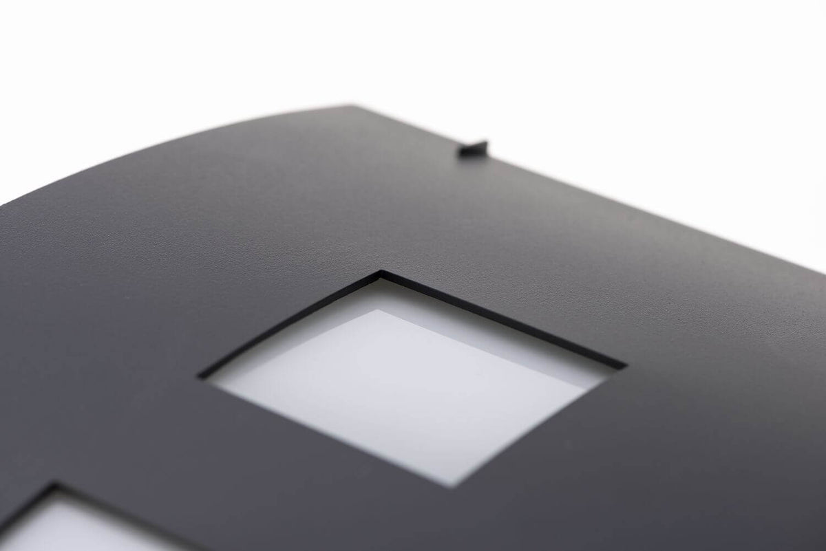Détail de la finition texturée anthracite et d'une découpe carrée laissant passer la lumière.