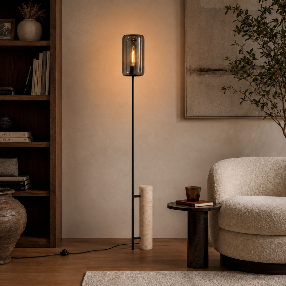 Lampadaire devant une bibliothèque, cylindre de verre fumé et socle minéral