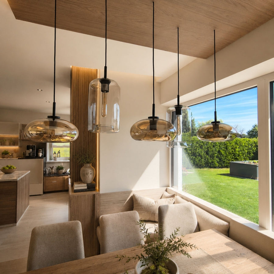 Quatre suspensions en verre ambré et transparent au-dessus d'une banquette près d'une baie vitrée.