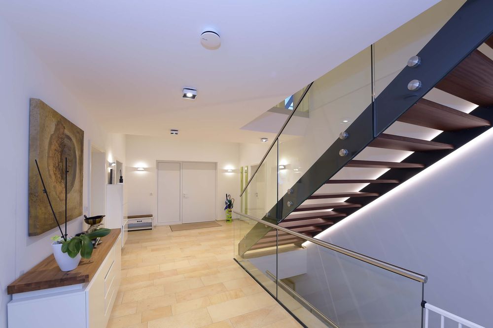 Mise en ambiance dans un hall moderne avec escalier et appliques murales discrètes.