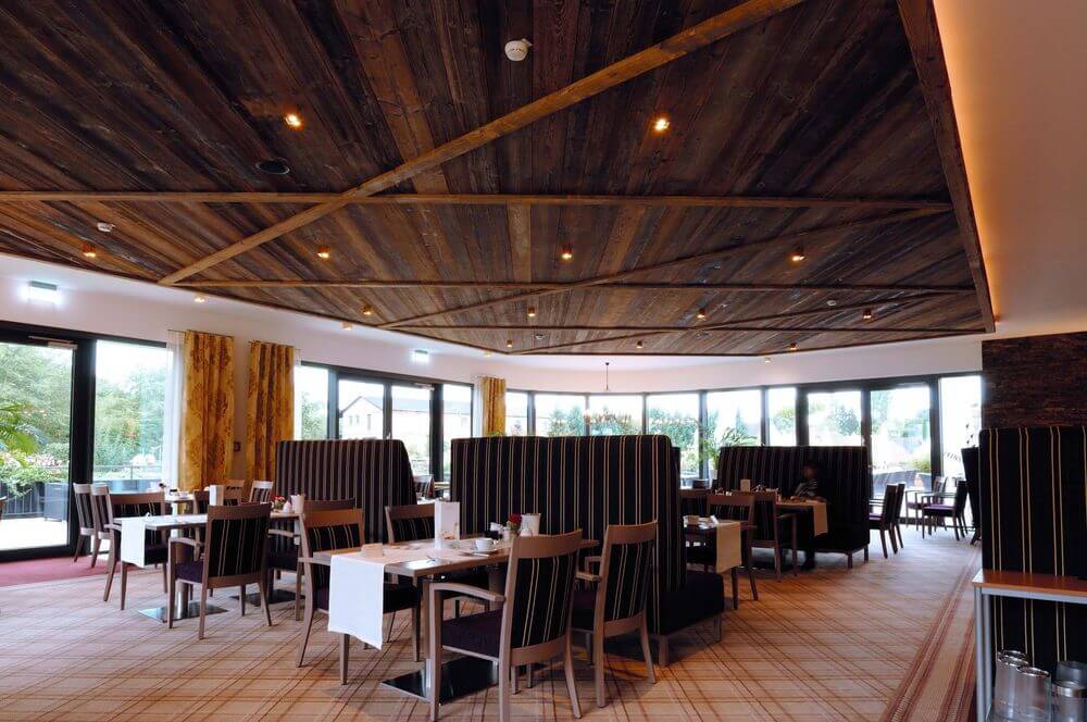 Mise en ambiance dans un restaurant, spots noirs fixés au plafond en bois.