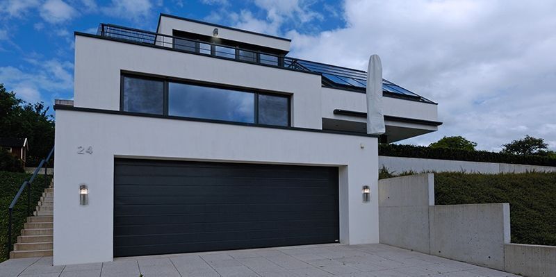Maison moderne blanche avec deux appliques murales grises installées près du garage