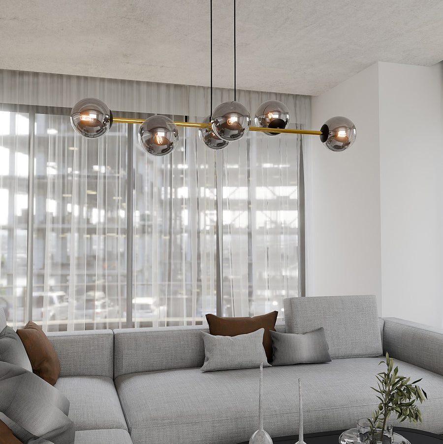 Suspension installée dans un salon lumineux, au-dessus d'un canapé gris et de coussins.