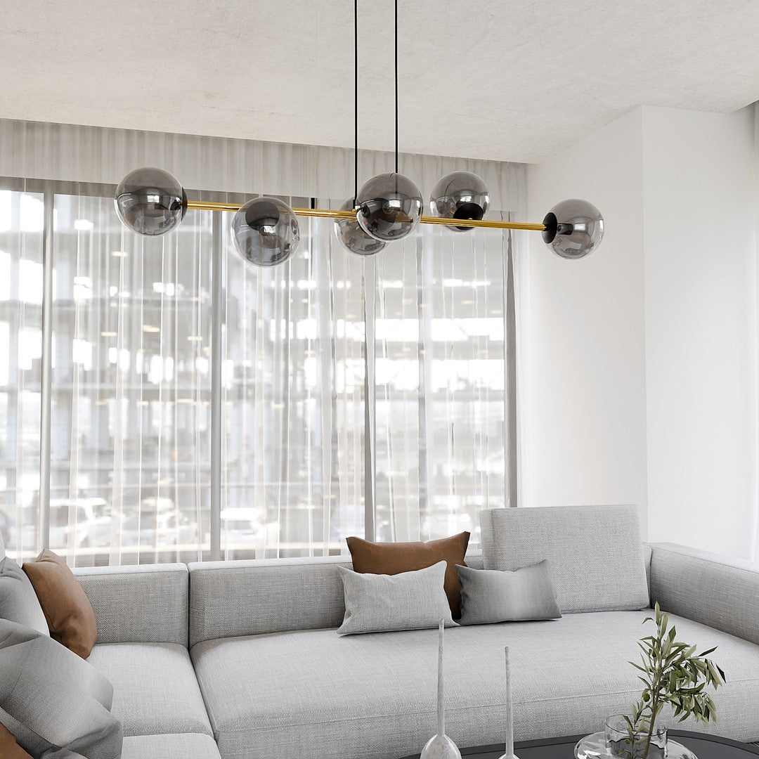 Luminaire suspendu dans un intérieur moderne, avec rideaux transparents et canapé gris clair.
