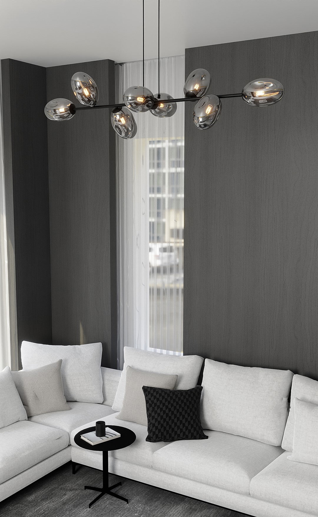 Mise en ambiance au-dessus d'un canapé clair, suspension allumée devant un mur gris anthracite.