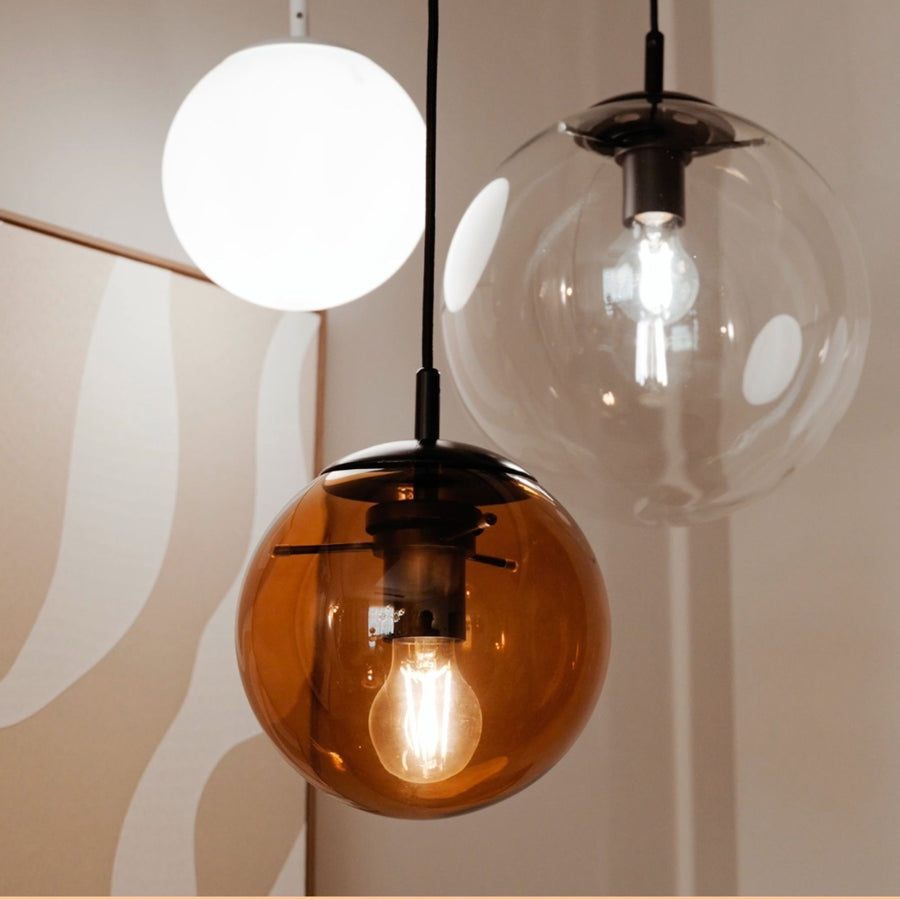 Détail finition : globes opalin, ambré et transparent, douilles noires et ampoules visibles.