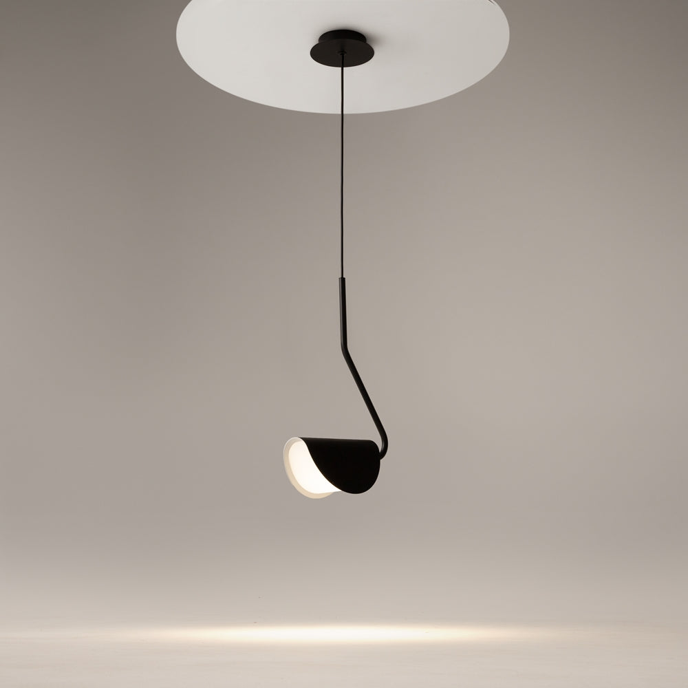 Mise en ambiance : luminaire suspendu diffusant une lumière chaude sur un mur beige.
