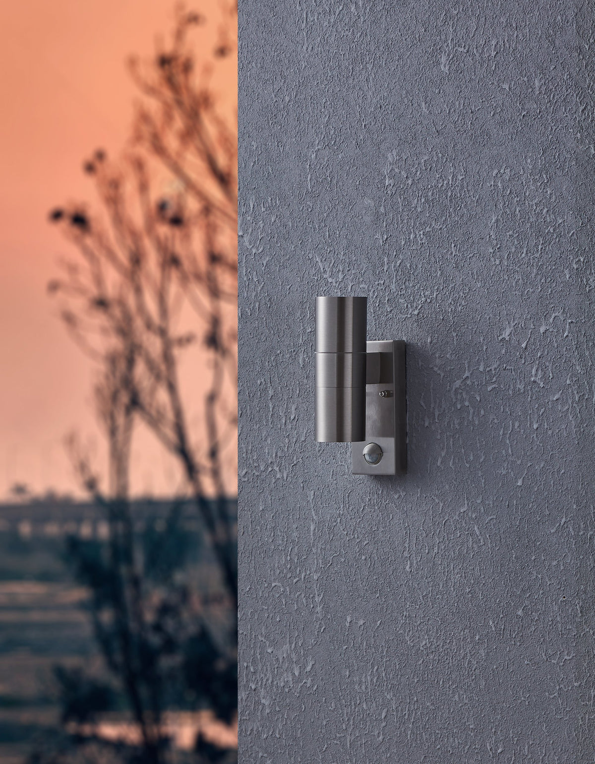Vue en situation de l'applique murale éclairant un mur extérieur crépi au crépuscule.