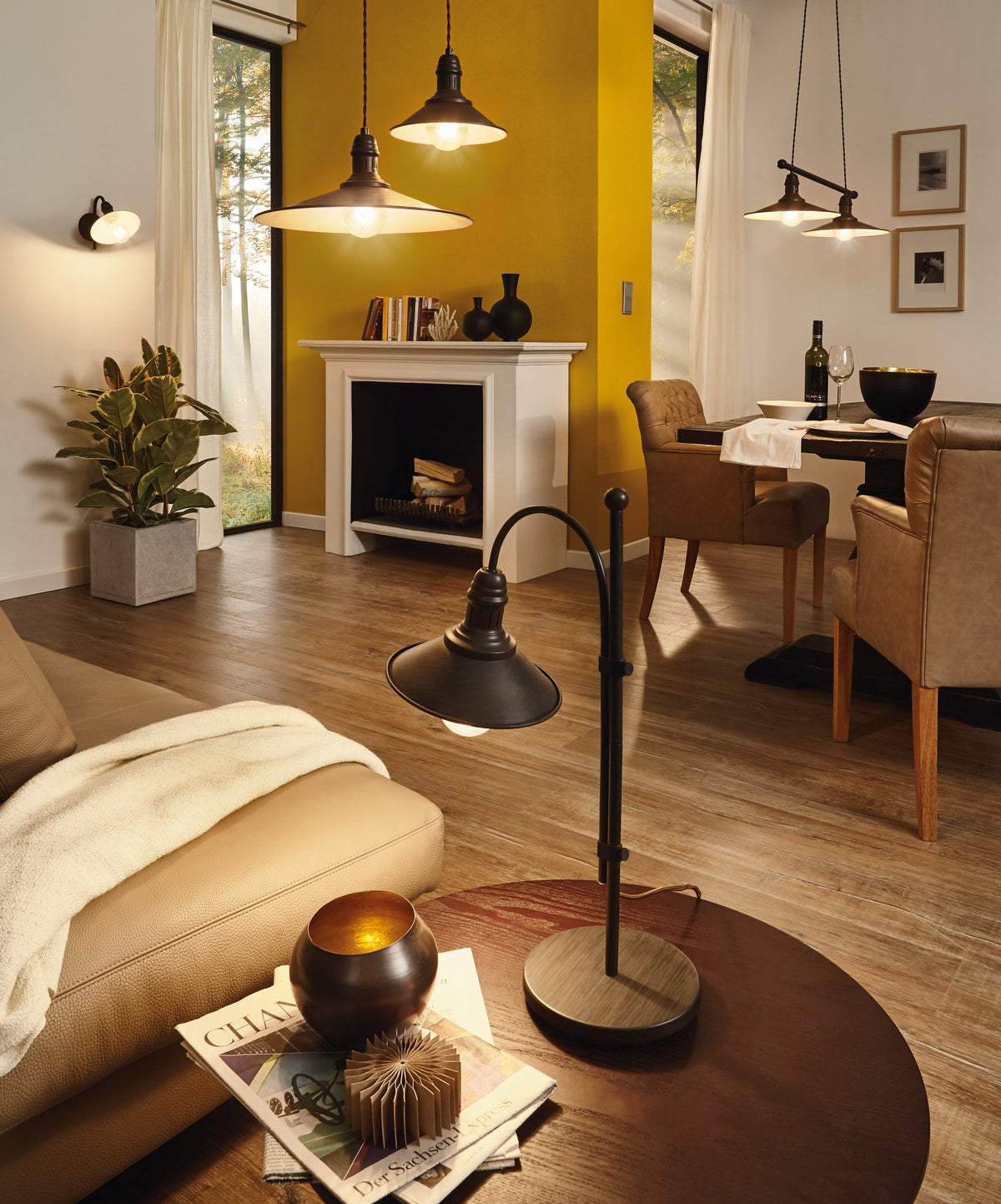 Mise en ambiance salon au mur jaune, plusieurs suspensions et lampadaire allumés