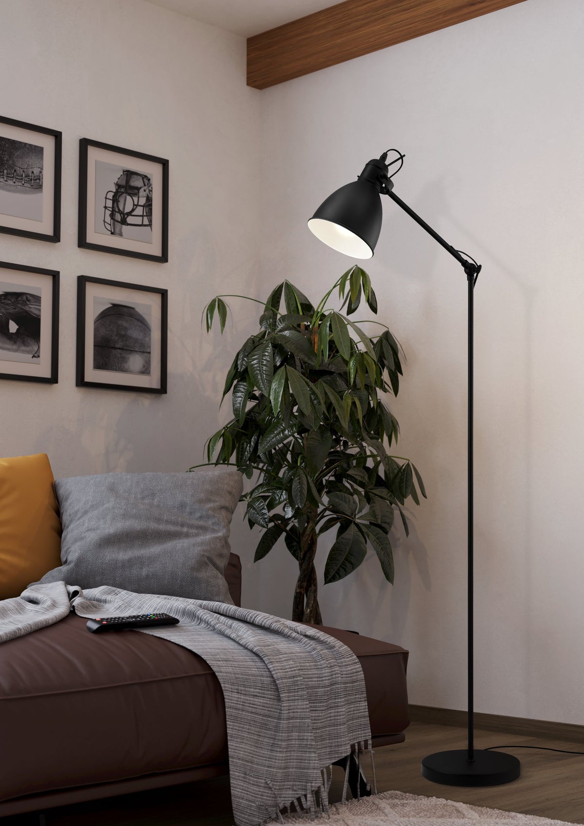 Lampadaire près d'un canapé marron, plante verte et cadres muraux