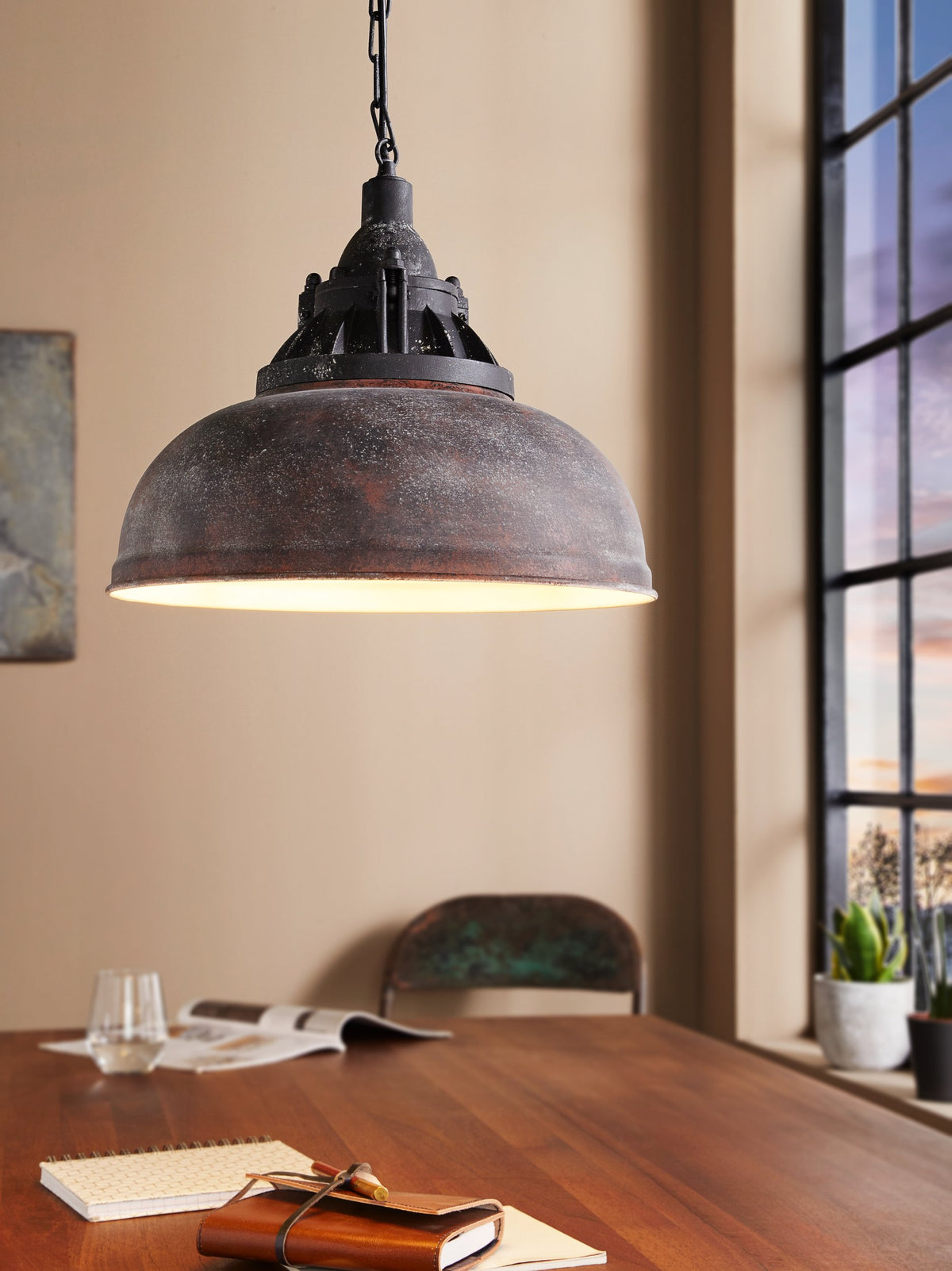 Mise en ambiance de la suspension au-dessus d'une table en bois avec carnet et verre.
