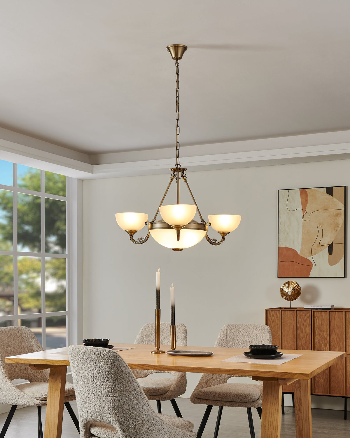 Mise en ambiance au-dessus d'une table en bois, luminaire allumé dans une salle à manger.