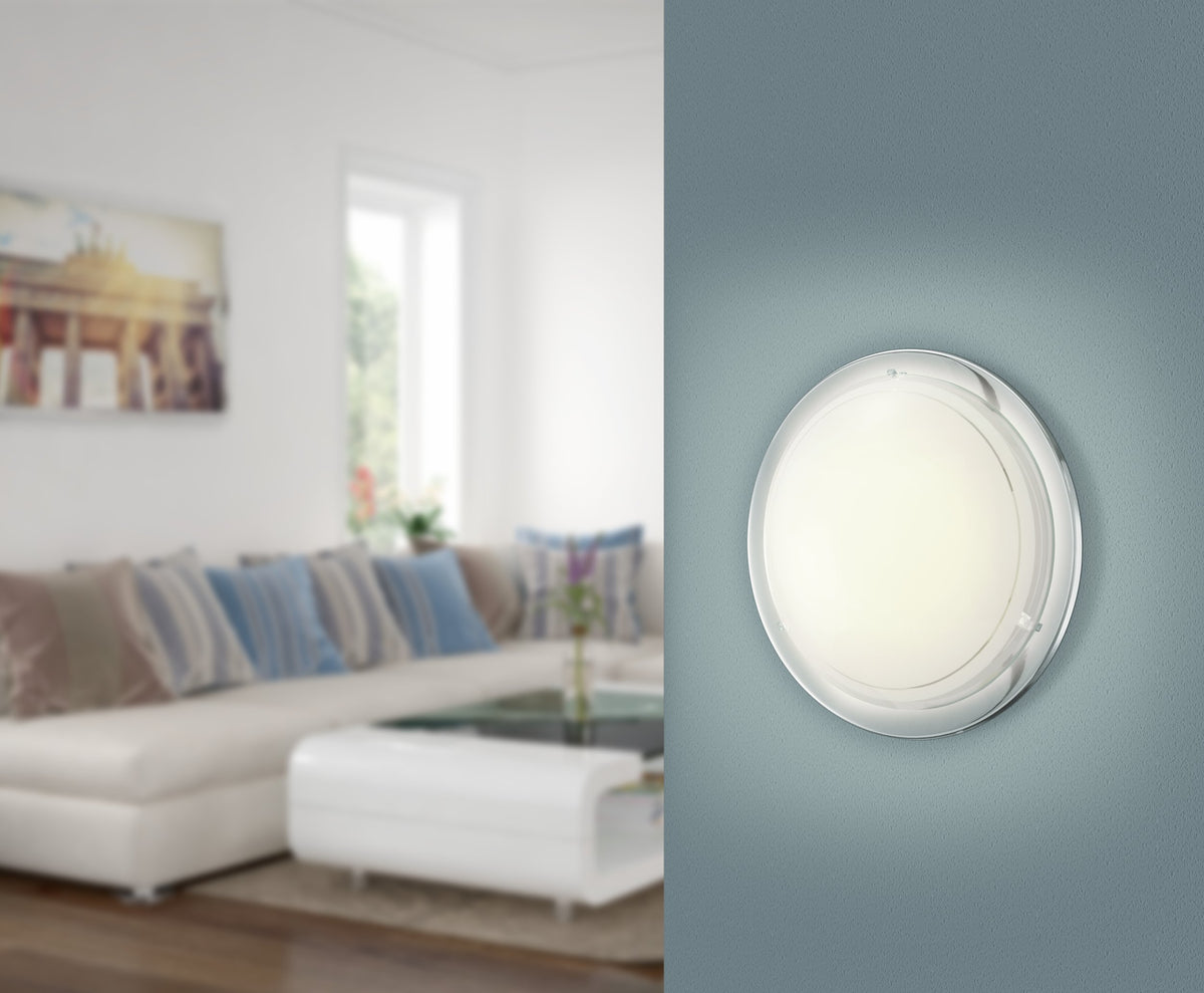 Luminaire rond allumé et fixé au mur bleu dans un salon moderne.