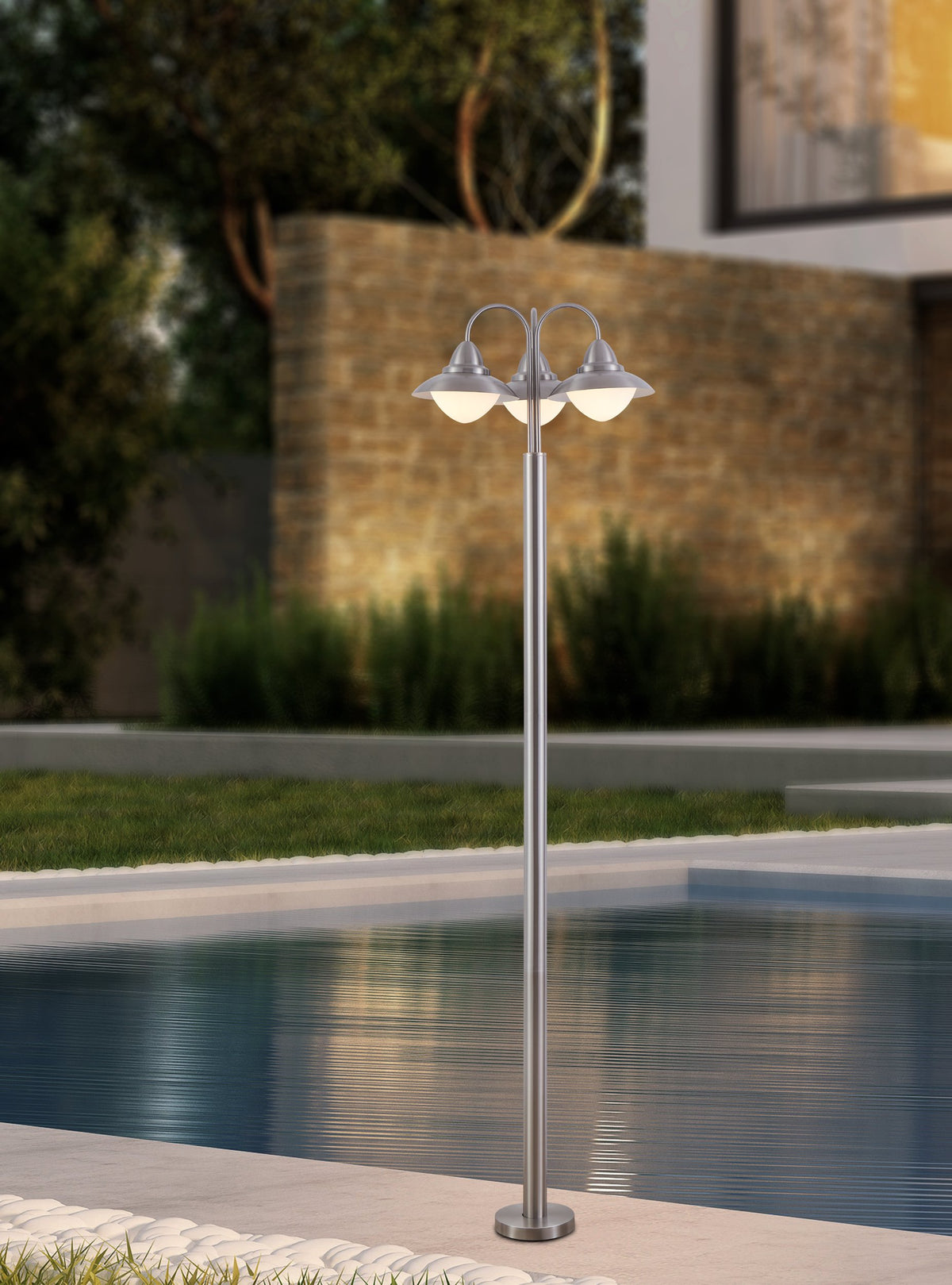 Mise en ambiance au bord d'une piscine, lampadaire allumé le soir près d'un mur