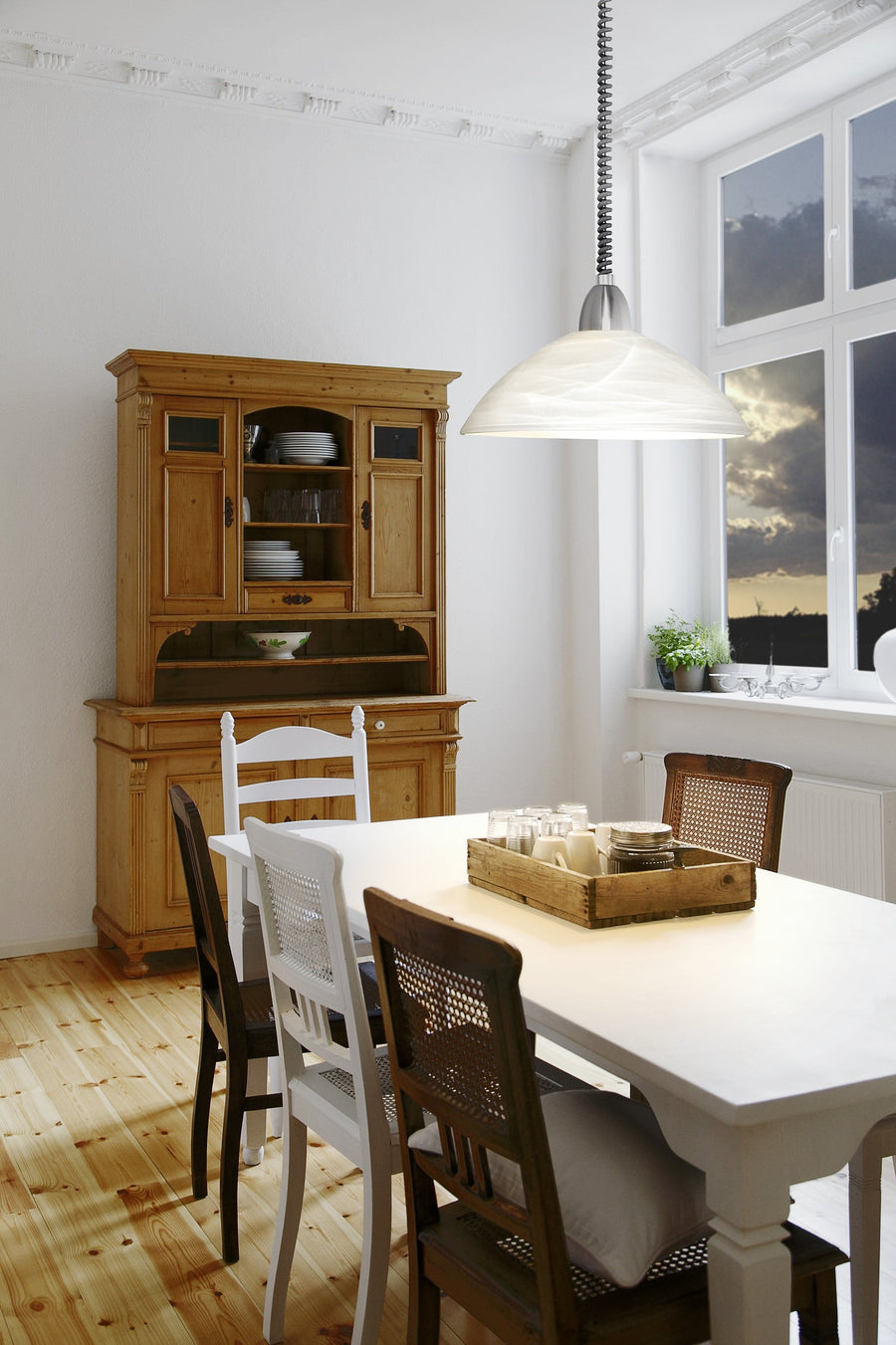 Suspension allumée au-dessus d'une table blanche dans une salle à manger rustique