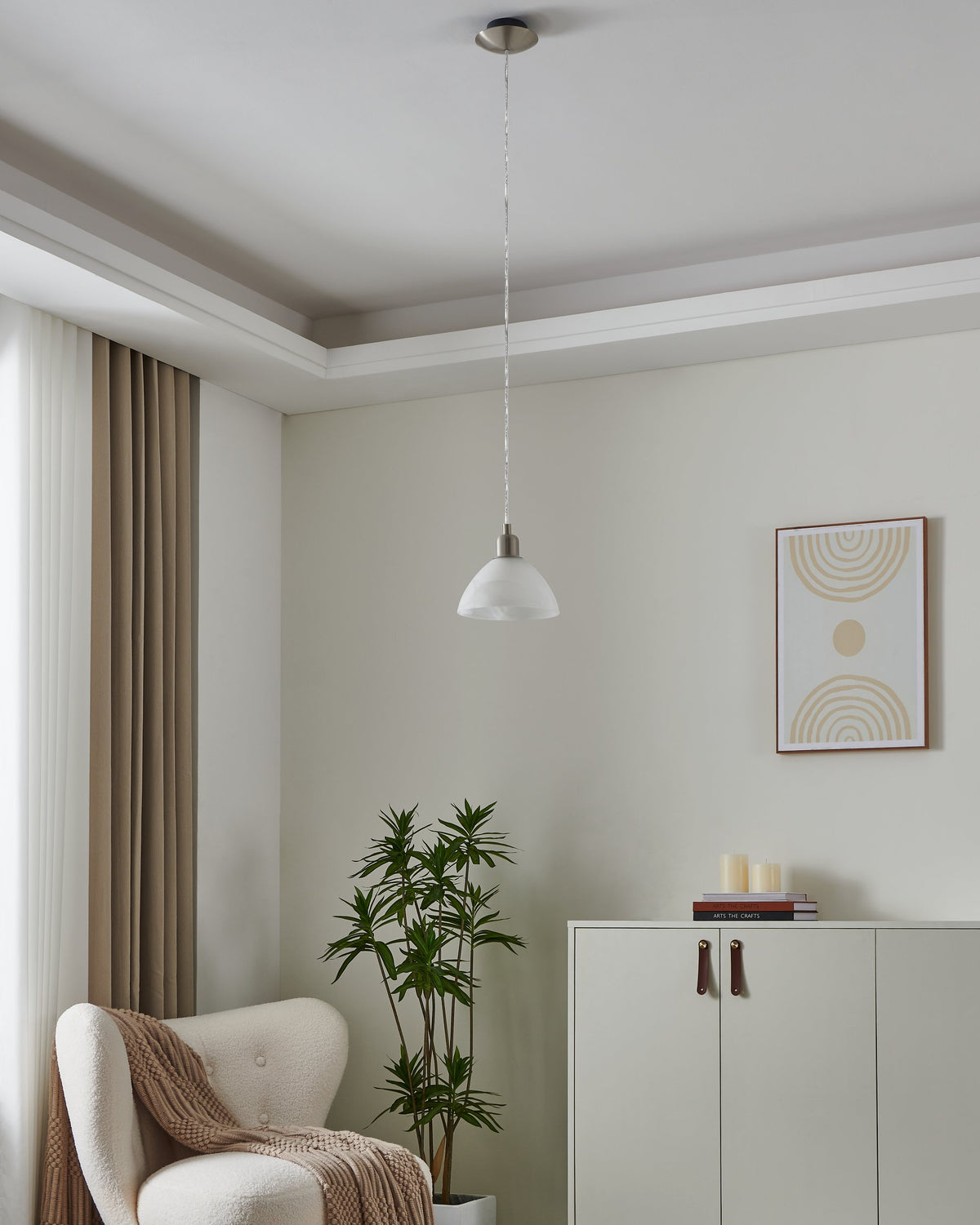 Mise en ambiance dans un salon clair, suspension allumée au-dessus d'un fauteuil
