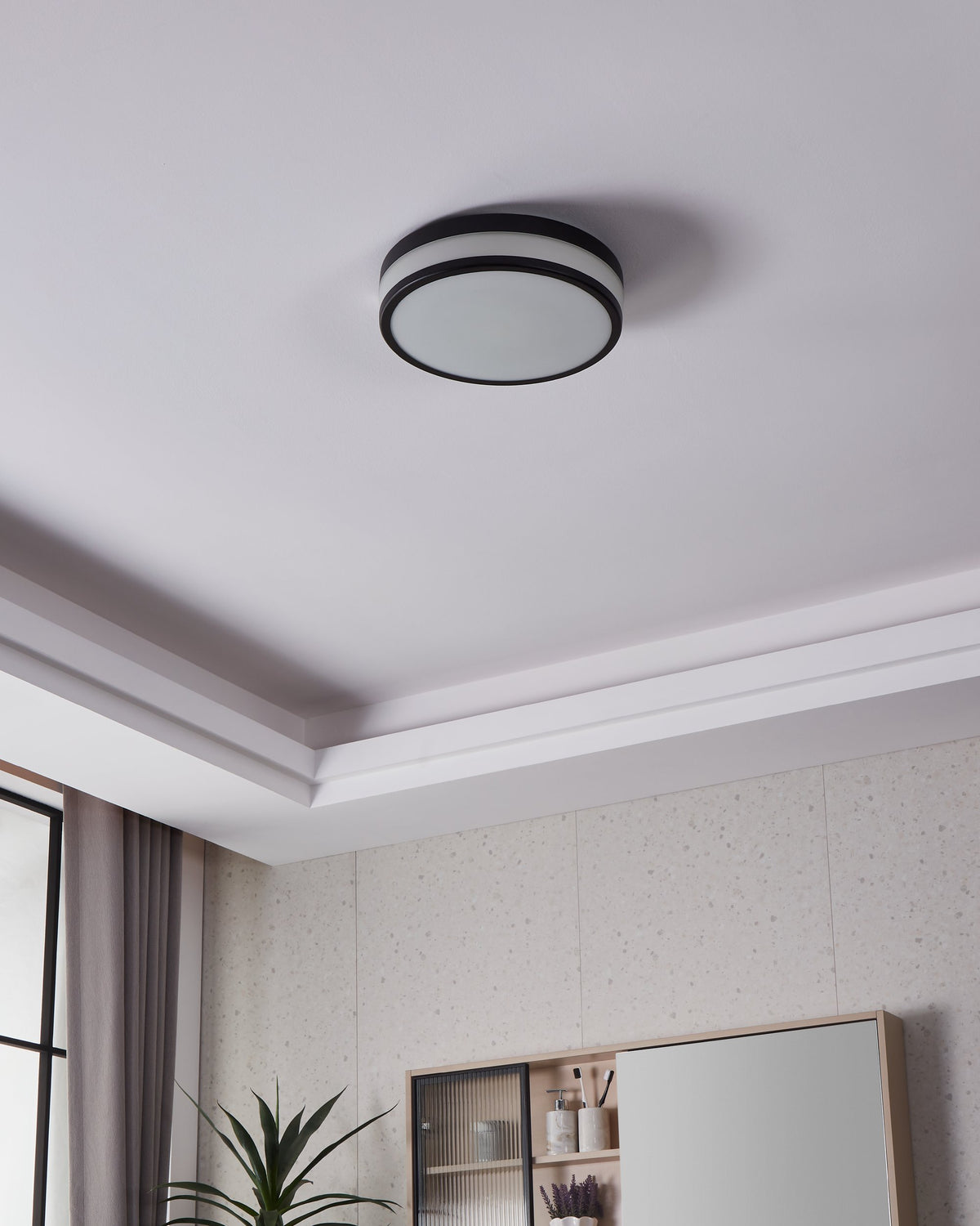 Plafonnier éteint fixé au plafond dans une pièce avec moulures et meuble.