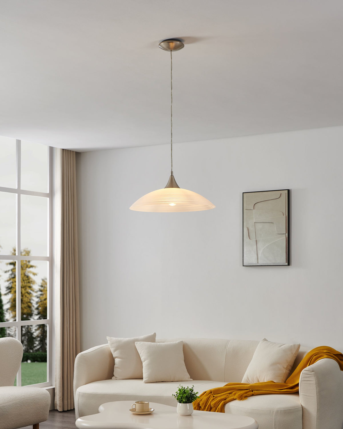 Mise en ambiance dans un salon clair, suspension allumée au-dessus du canapé