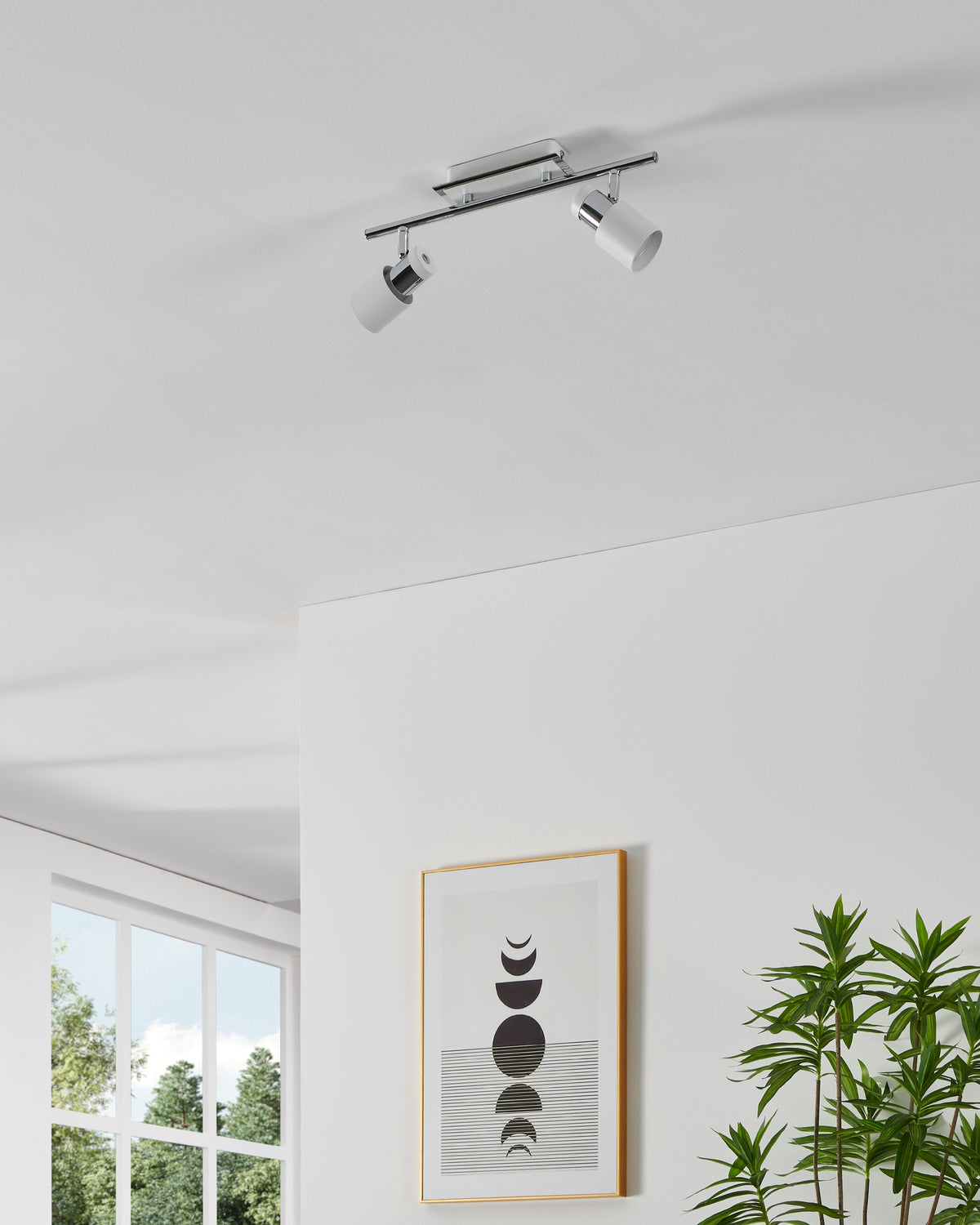 Spot double installé au plafond, têtes blanches orientées vers le bas, intérieur clair.