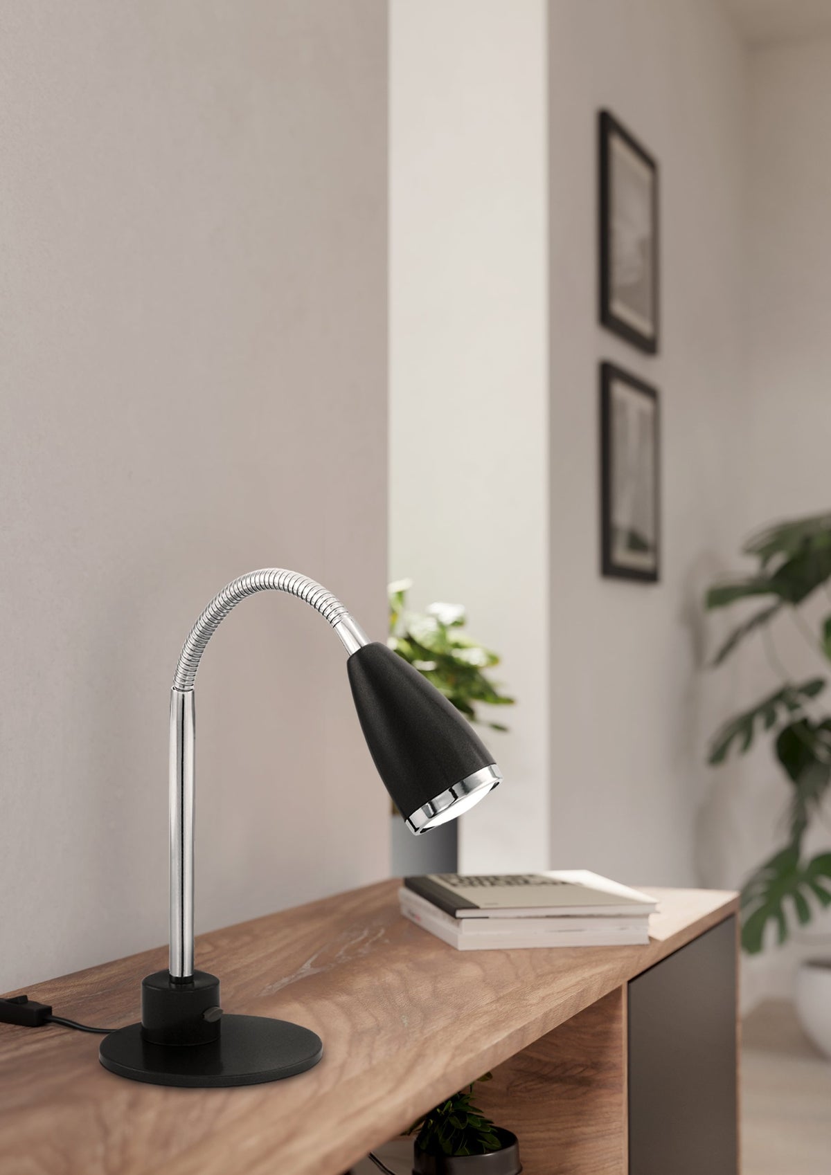Lampe de table noire posée sur un meuble en bois avec livres.