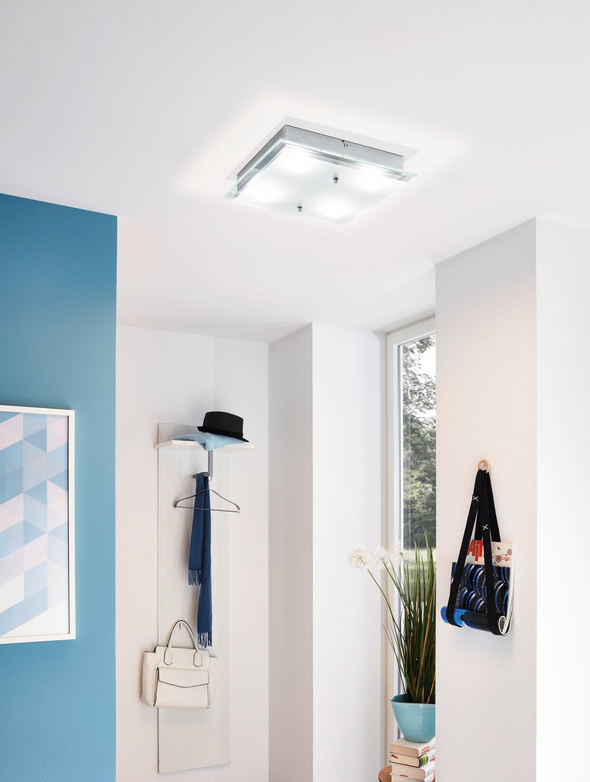 Mise en ambiance dans une entrée claire, plafonnier allumé au-dessus d'un portemanteau
