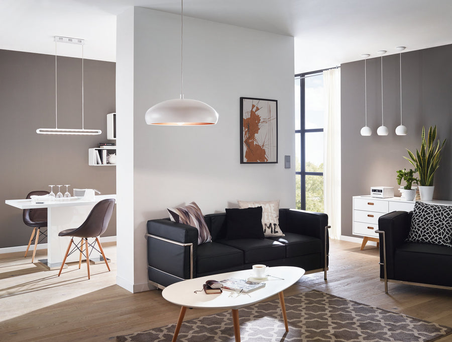 Suspension installée au-dessus d'un salon moderne avec canapé noir et fauteuils