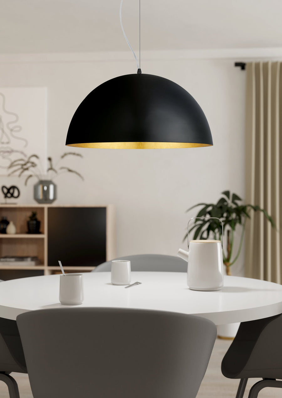 Suspension noire et dorée suspendue au-dessus d'une table ronde blanche.