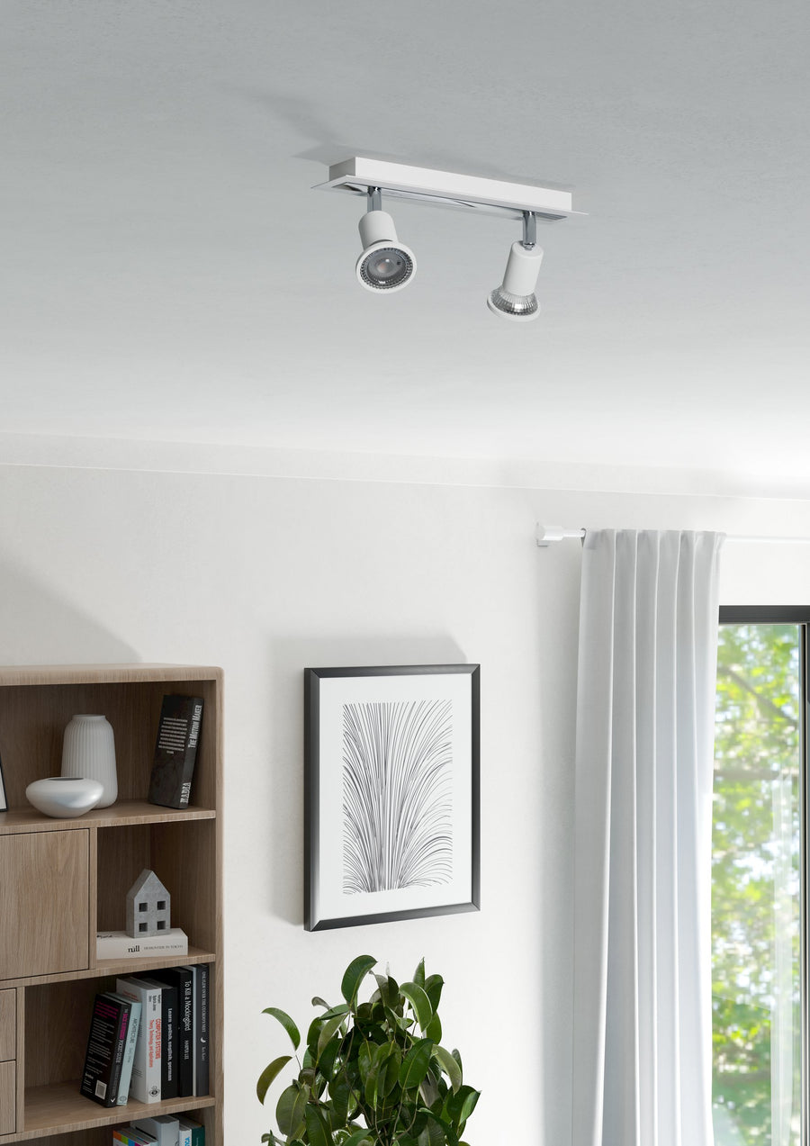 Vue du plafonnier allumé dans un salon clair, spots orientés vers le mur