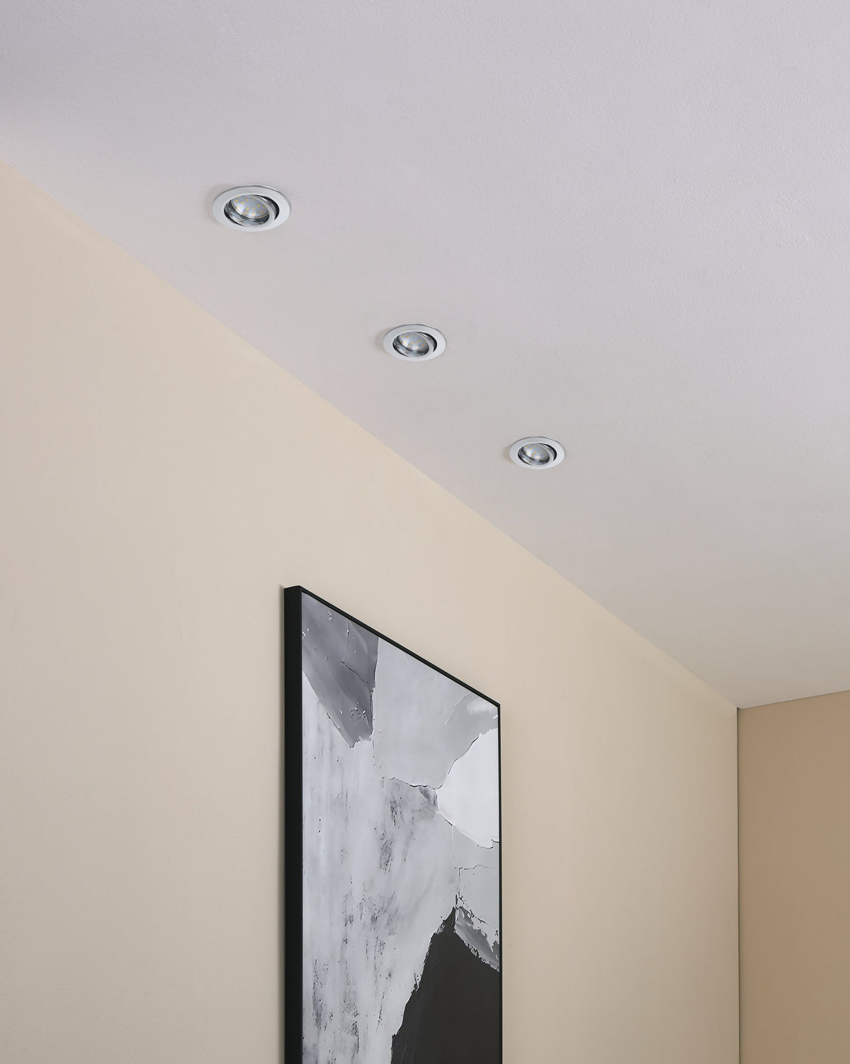 Trois spots encastrés fixés au plafond au-dessus d'un tableau encadré