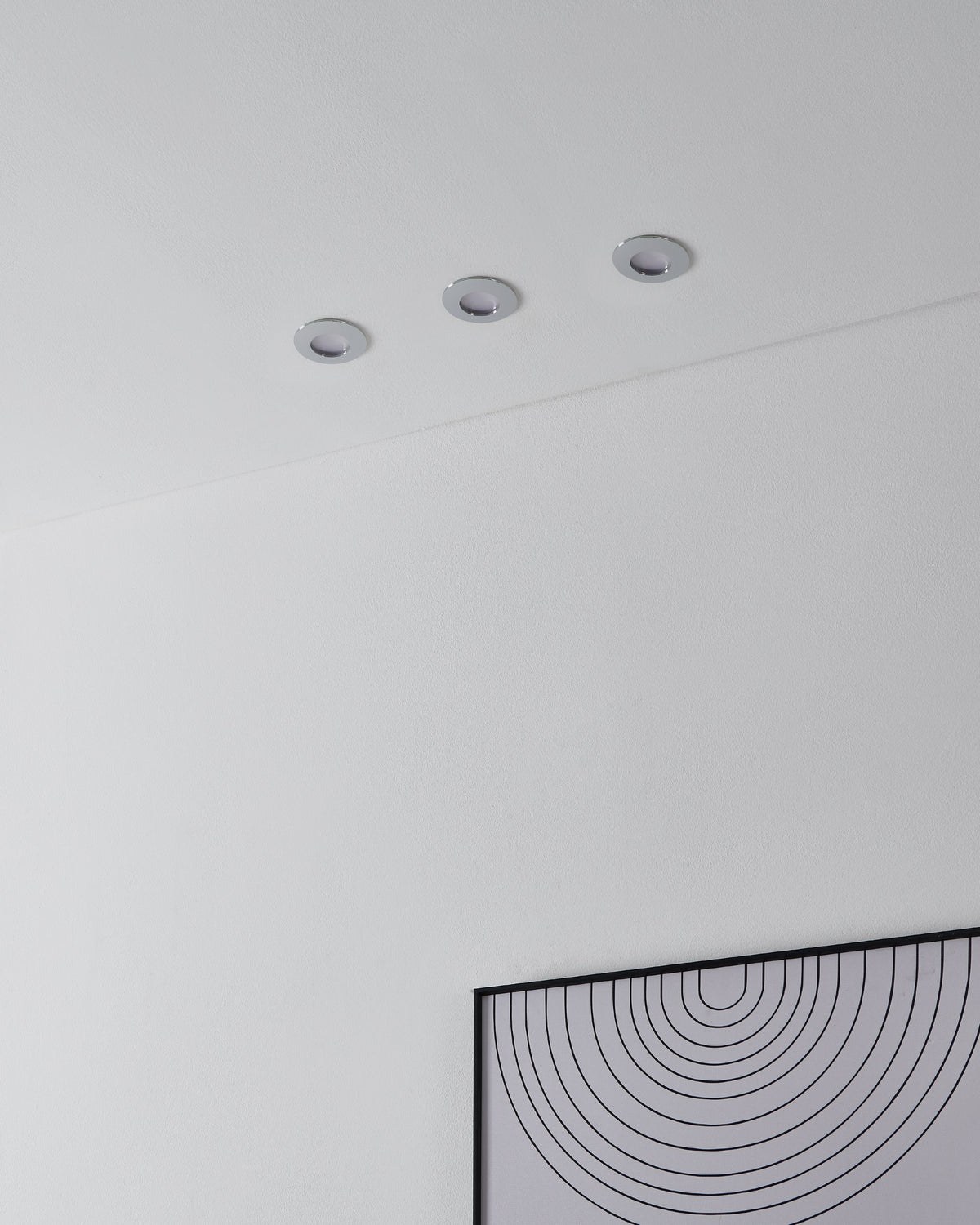 Trois spots encastrés éteints affleurant un plafond blanc, rendu discret