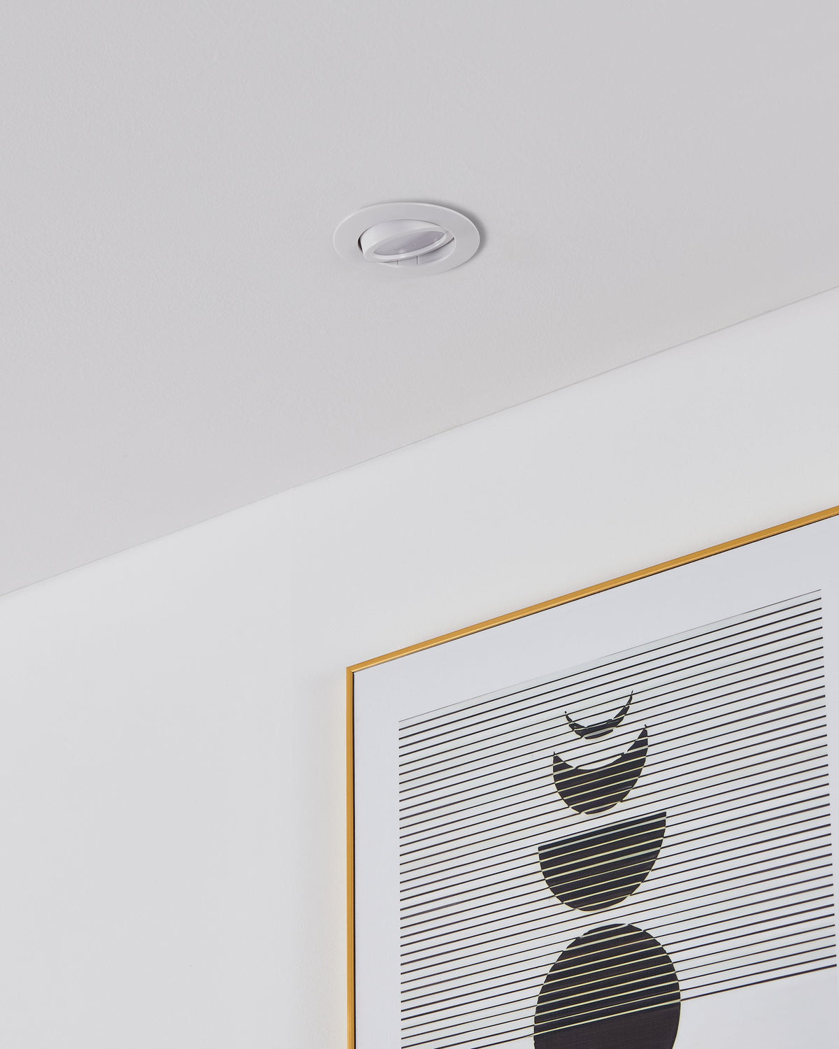 Spot encastré blanc installé dans un plafond, au-dessus d'un cadre doré