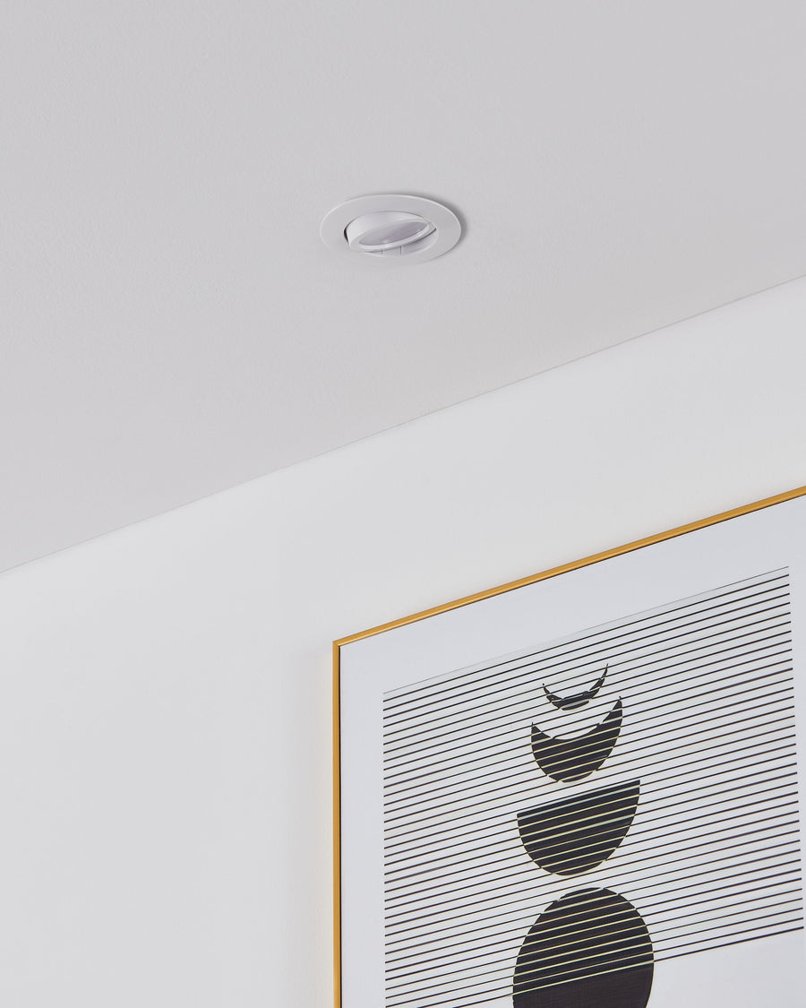 Spot encastré blanc installé dans un plafond, au-dessus d'un cadre doré