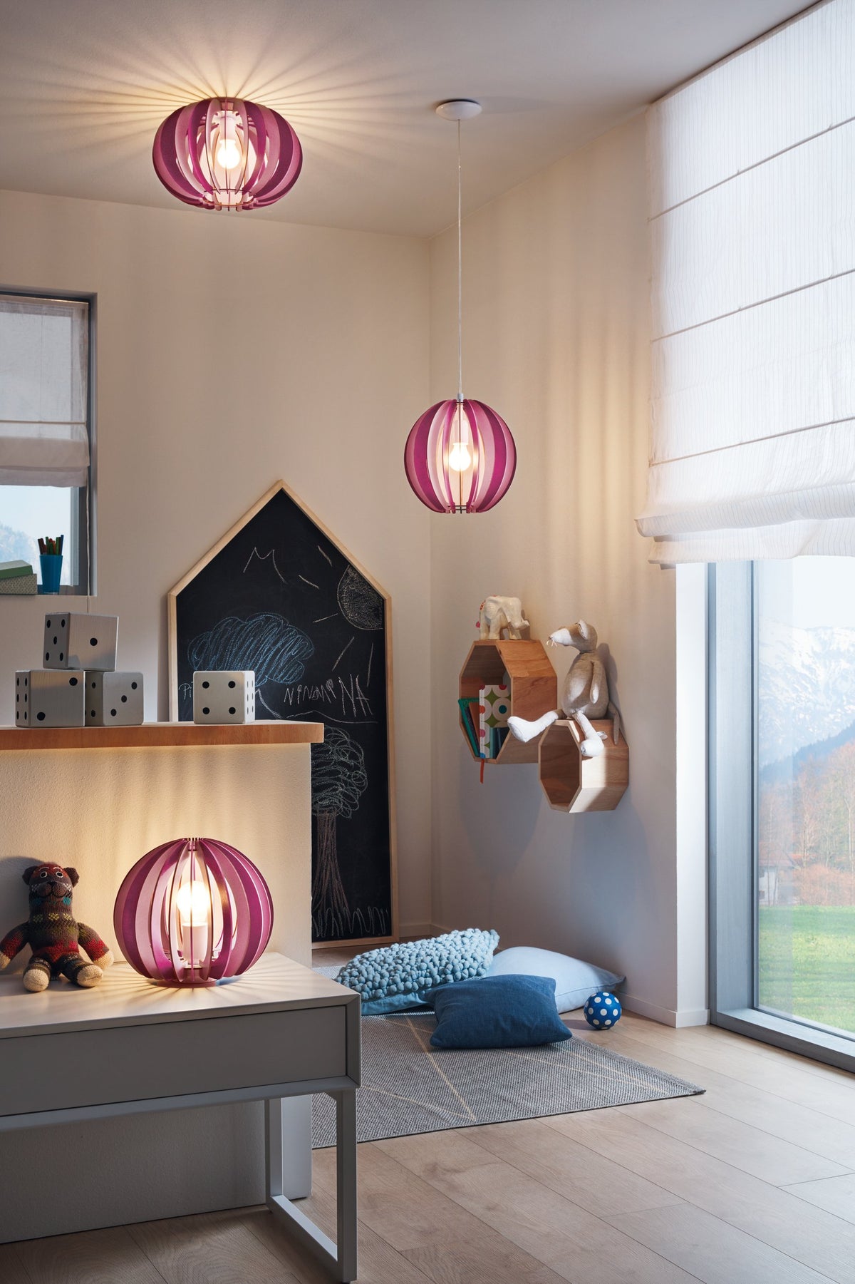 Mise en ambiance dans une chambre d'enfant avec la lampe rose posée sur un bureau.