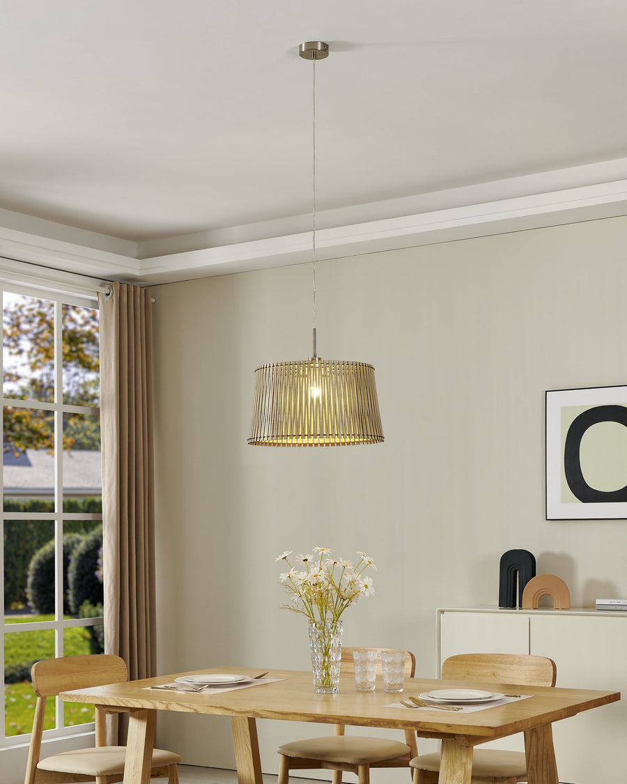 Suspension allumée au-dessus d'une table à manger en bois clair dans une pièce lumineuse.