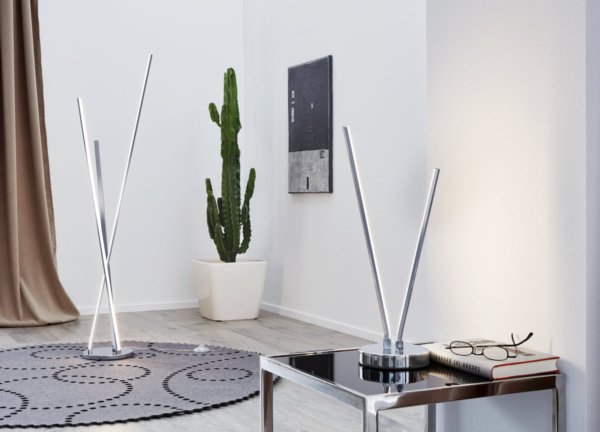 Mise en ambiance dans un salon, deux lampes chromées posées sur table et au sol