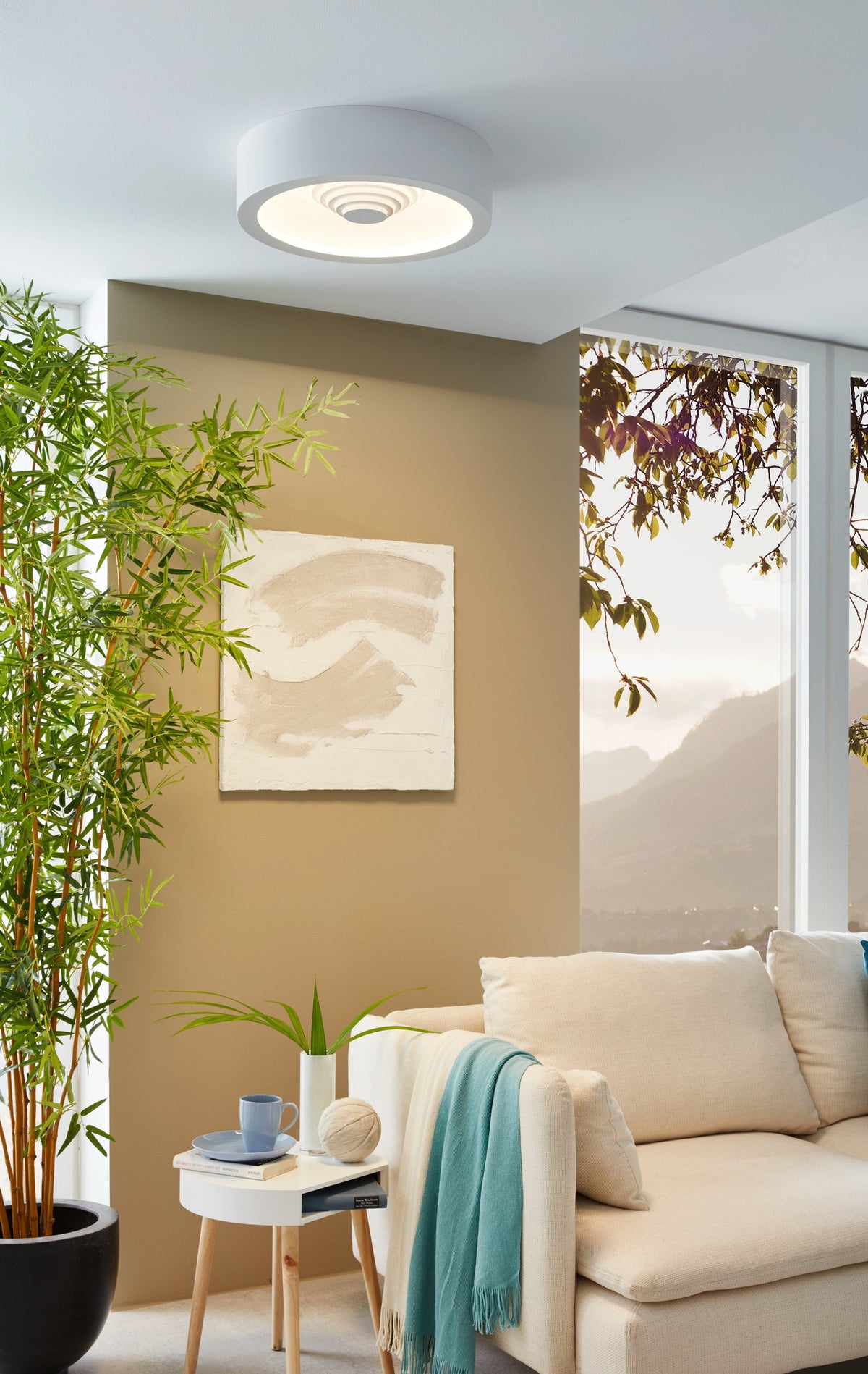 Mise en ambiance du plafonnier allumé dans un salon beige avec sofa et bambou