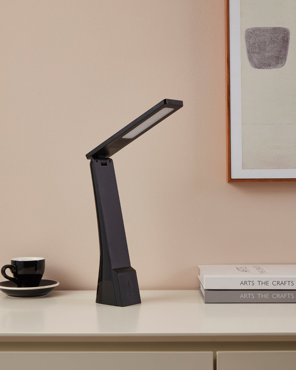 Lampe posée sur un buffet, profil éteint près d'une tasse noire.