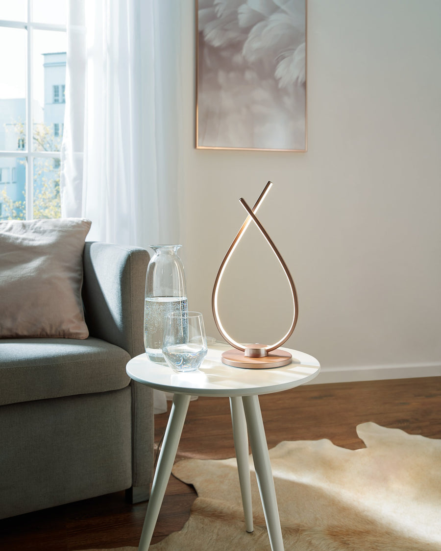 Lampe allumée sur table basse, carafe et verre d'eau à côté