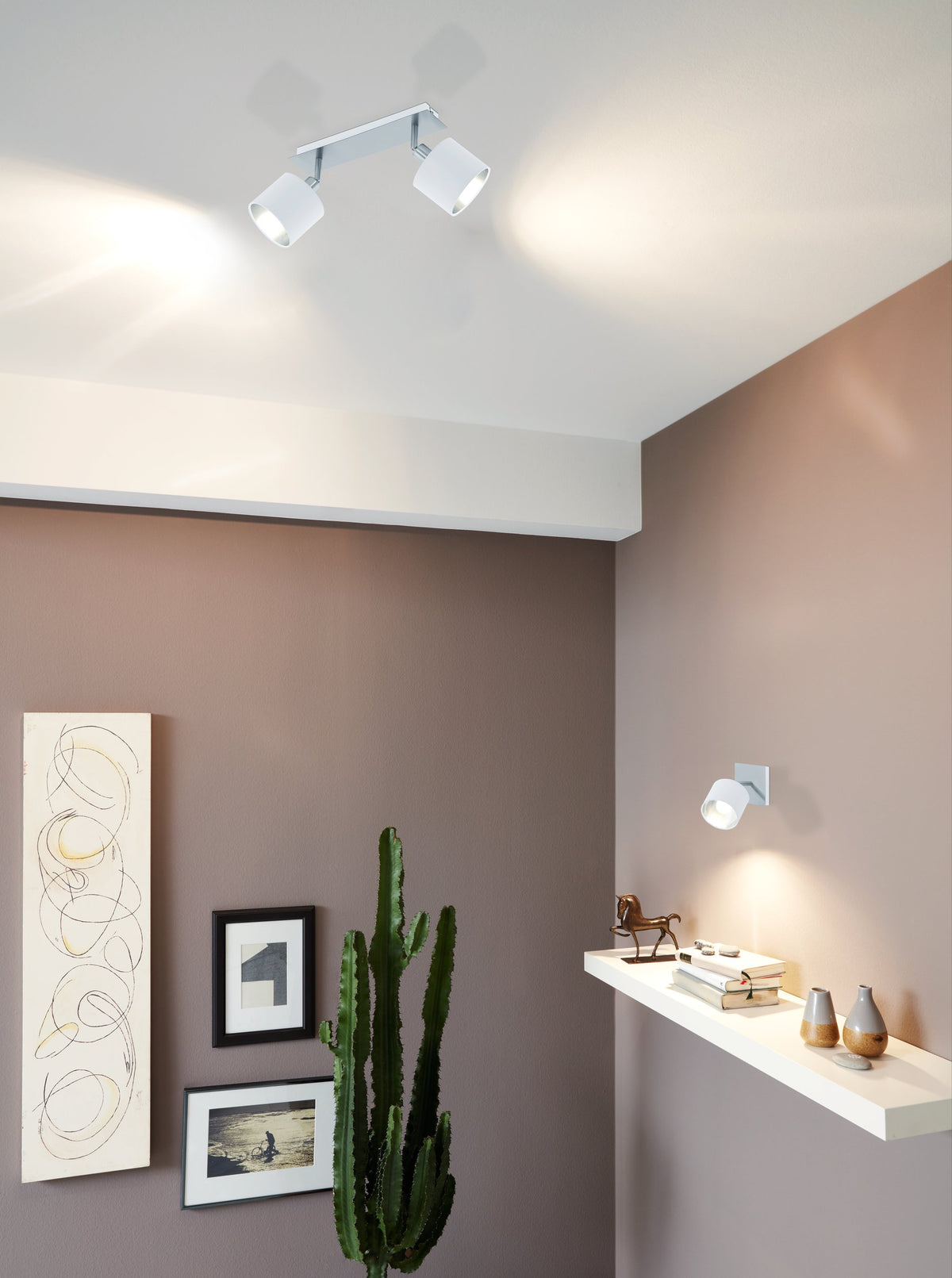 Mise en ambiance plafond dans un salon, deux spots éclairant mur et étagère décorée.