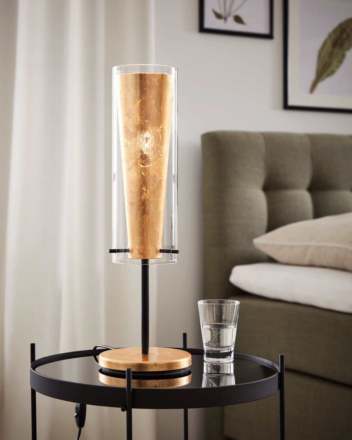 Mise en ambiance sur une table d'appoint près d'un lit, lampe allumée.