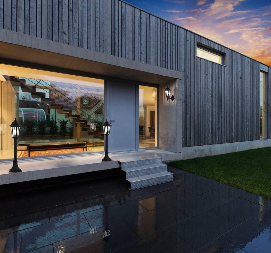 Vue de nuit d'une maison moderne avec l'applique murale noire fixée près de l'entrée.