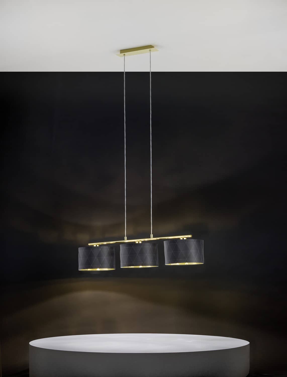 Suspension allumée dans une ambiance sombre, au-dessus d'une table ronde.