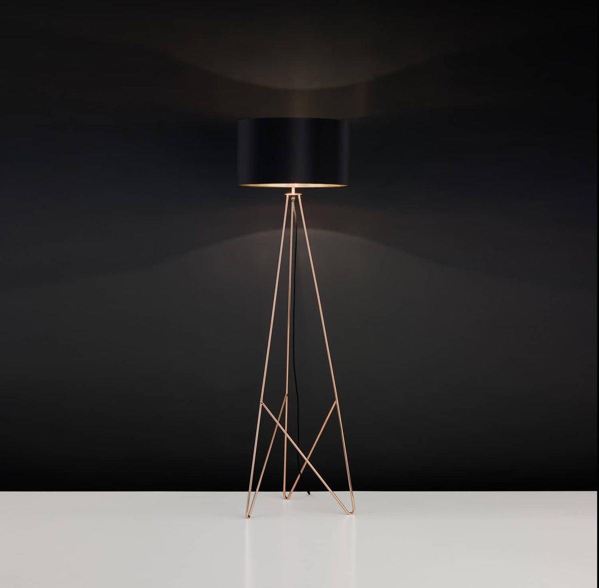 Mise en ambiance sombre du lampadaire allumé, abat-jour noir et structure dorée.