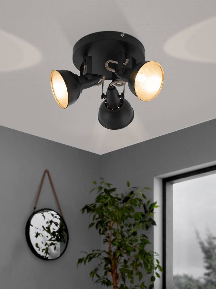 Luminaire allumé au plafond dans un salon gris avec plante et miroir